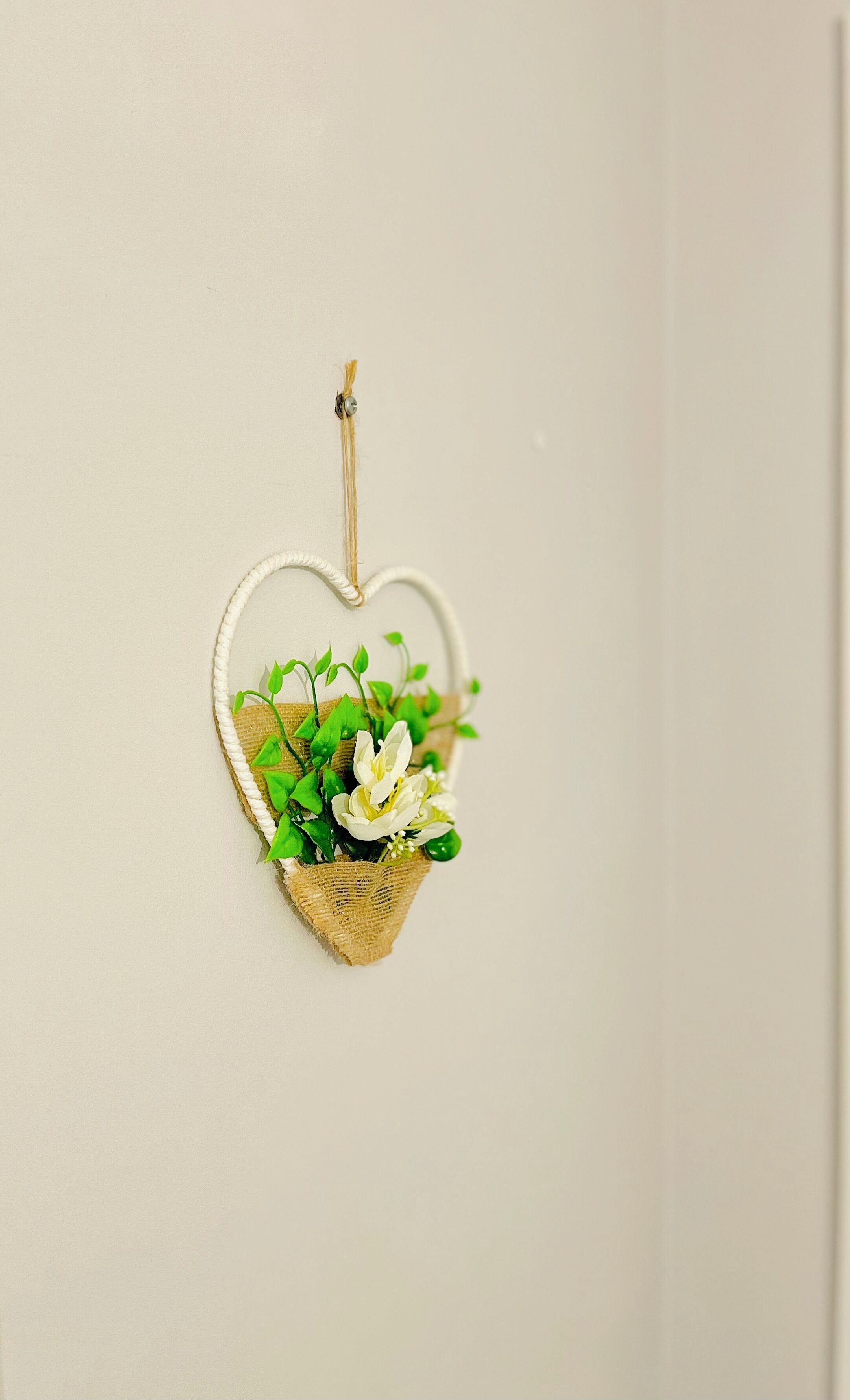 A heart-shaped hanging decoration with a small plant.