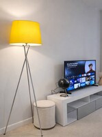Un soggiorno moderno con una lampada da terra, una televisione e un mappamondo decorativo.