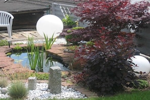 A garden with a pond, white spherical decorations, and a red-leafed bush. - Holiday home with 1 bedroom (Gossersweiler-Stein)