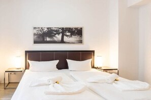 A hotel room with a large bed, two bedside tables, a headboard, and a framed picture on the wall. - Holiday apartment with 2 bedrooms (Ostseebad Heringsdorf)