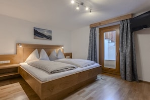 Ein Schlafzimmer mit einem hölzernen Bett, einem Nachttisch, einem Fenster mit Vorhängen und einem Bild an der Wand.