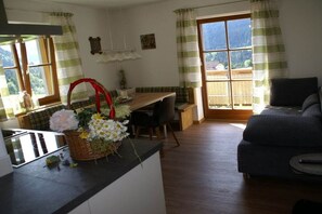 Ein gemütliches Wohnzimmer mit einer Couch, einem Essbereich mit Tisch und Stühlen sowie einer Küchenzeile mit einer Arbeitsplatte und einem Blumenkorb.