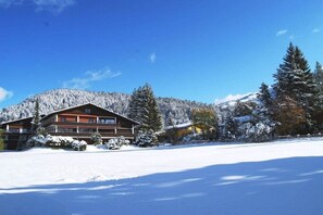A lodge with a large building, snow-covered trees, and a mountain in the background.