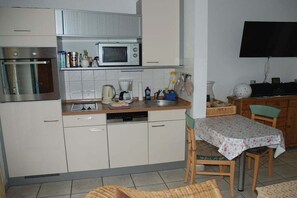 Eine kleine Küche mit Mikrowelle, Backofen und Geschirrspüler. Es gibt einen Essbereich mit Tisch und Stühlen.