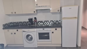 A compact kitchen with a washing machine, a built-in oven, and a refrigerator. - Gite "La Nayade" 2 pers air-conditioned center Vallon Pont d'Arc (Vallon-Pont-d'Arc)
