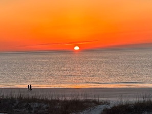 A sunset over a beach with two people walking along the shore. - Admirals Row, Ocean Front Villa-Hilton Head Beach and Tennis (Hilton Head Island)