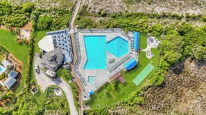 Ein Luftbild eines Resorts mit einem großen Schwimmbad, mehreren Gästezimmern und einem gepflegten Rasen.