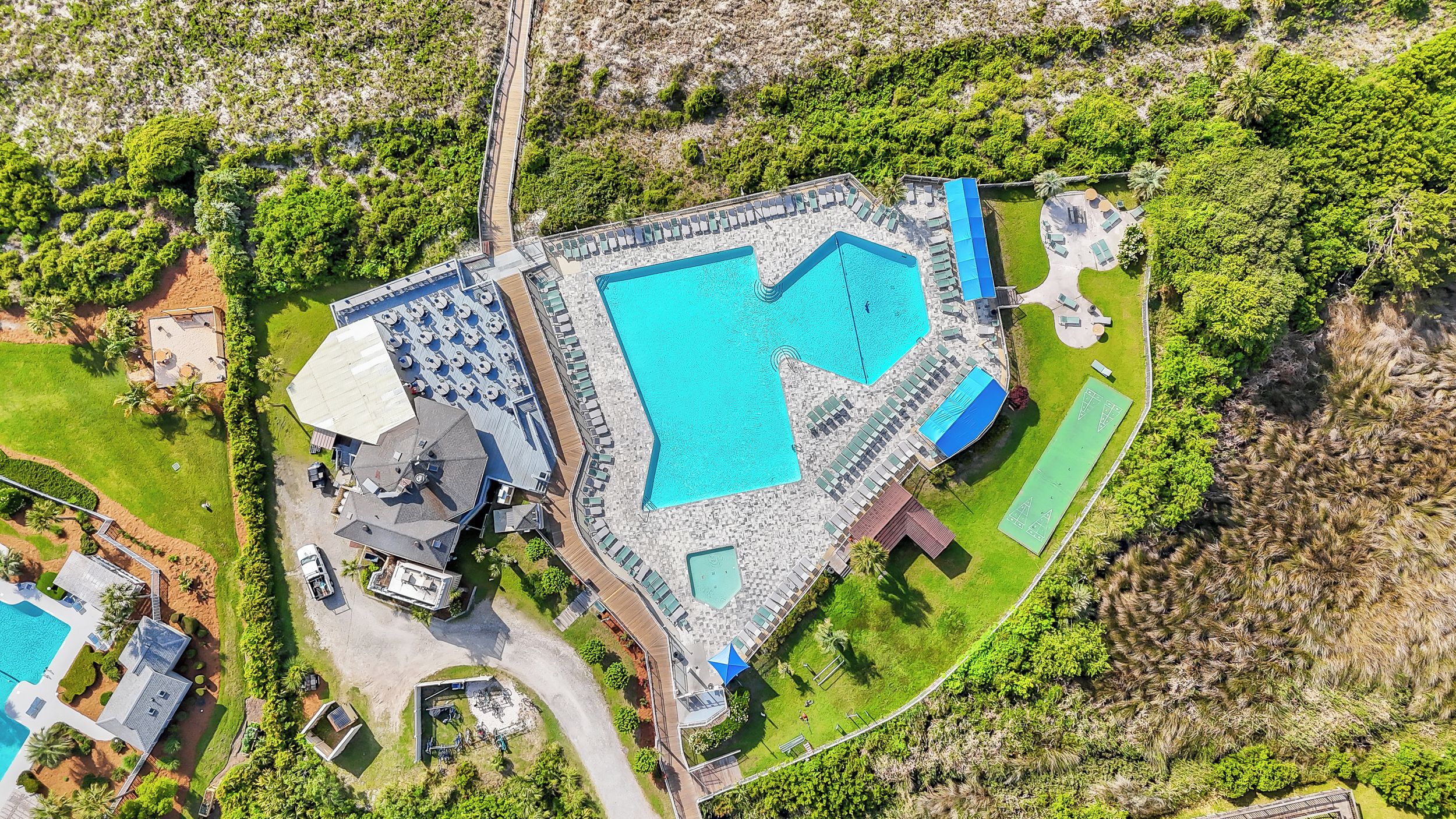 Eine Luftaufnahme eines Resorts mit einem großen Pool, mehreren Liegebereichen und einer gepflegten Landschaft.
