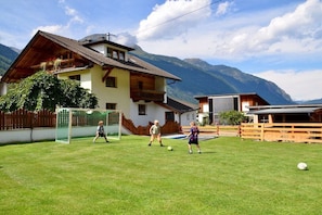 Ein Haus mit geneigtem Dach, einem Balkon und einem Berg im Hintergrund.