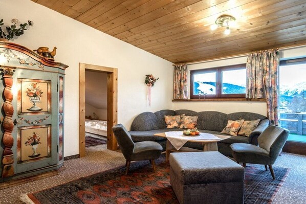 A cozy room with a sofa, chairs, a table, and a vintage cabinet.