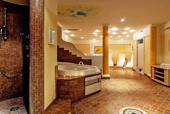 Une salle de bain spacieuse avec une grande baignoire, un espace douche et un sol carrelé.