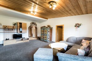 Ein Wohnzimmer mit einer Couch, einem kleinen Tisch, einem Fernseher und einem Schrank.