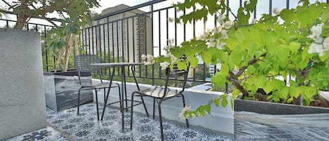 A balcony with a tiled floor, two chairs, a table, and a railing.