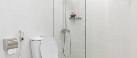 A modern bathroom with a toilet, a shower enclosure, and a towel rack.