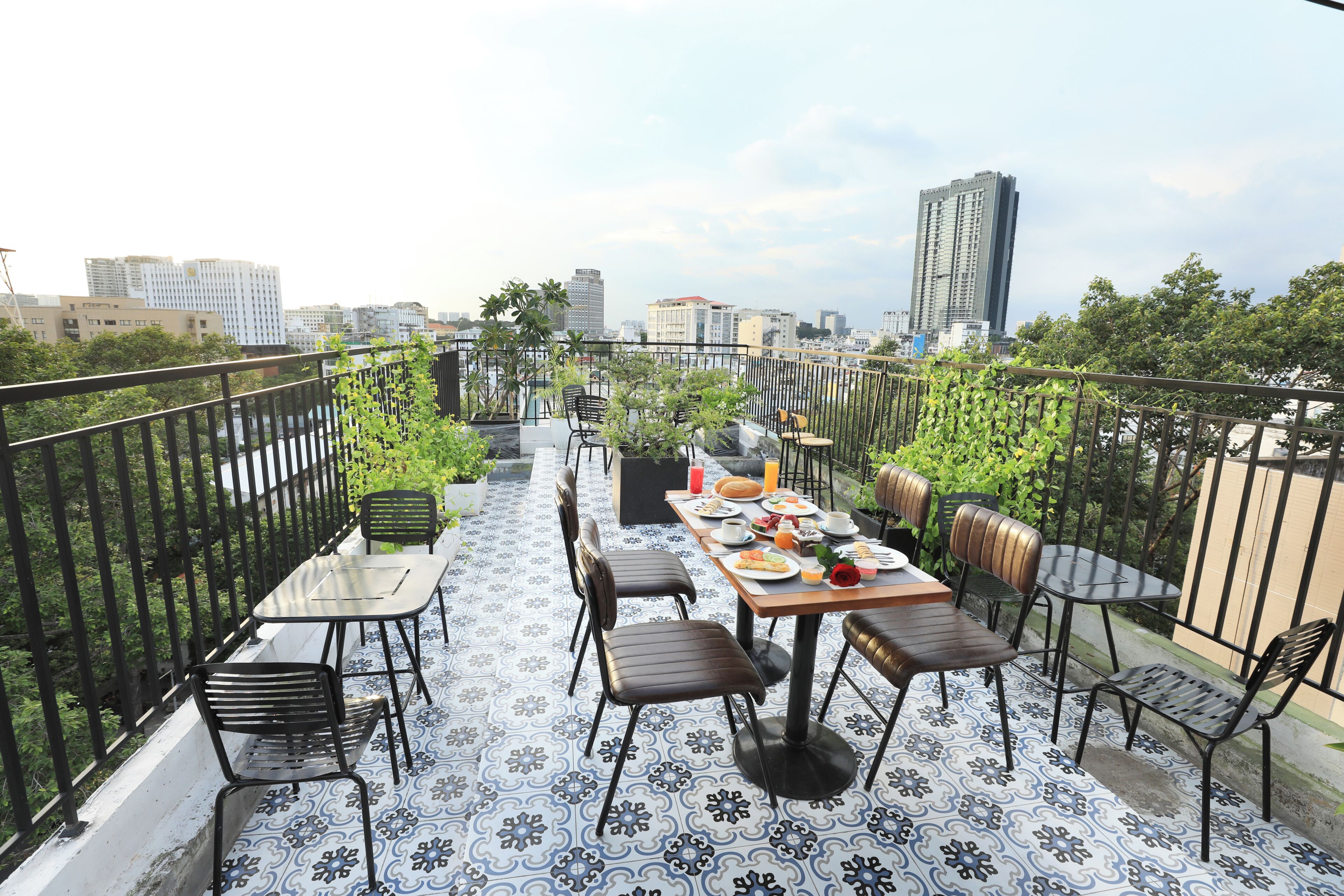 Une terrasse sur le toit avec une table à manger pour deux personnes, entourée de chaises, et une vue sur le paysage urbain en arrière-plan.