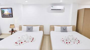Habitación de hotel con dos camas, un cuadro en la pared, un equipo de aire acondicionado y un armario de madera.