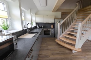 Eine moderne Küche mit Backofen, Spüle und einer Holztreppe.