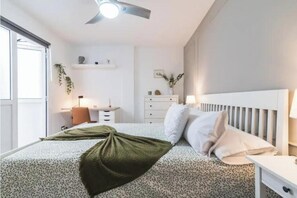 A bedroom with a bed, bedside tables, a ceiling fan, a window, and a wall-mounted shelf. - Bakea Home Gran Canaria. 10mins from the beach and the airport. (Ingenio)