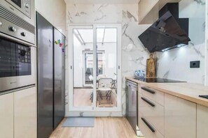 A modern kitchen with a built-in oven, a refrigerator, a dishwasher, and a wooden countertop. - Bakea Home Gran Canaria. 10mins from the beach and the airport. (Ingenio)