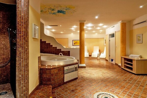 Ein geräumiges Badezimmer mit einer großen Badewanne, einer Duschkabine und Fliesenboden.