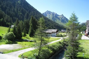 A mountain landscape with a building, a road, and a river. - 1 in the Bohemia House (Gargellen)