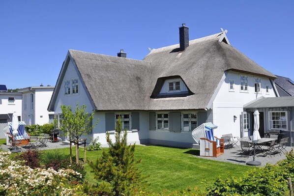 A house with a steeply pitched roof, a well-maintained lawn, and outdoor seating area. - Holiday home in Glowe with swimming pool (Glowe)