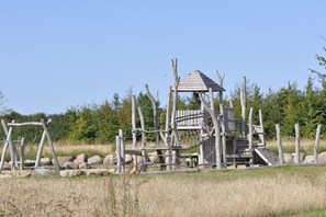 A wooden play structure with a climbing wall and a lookout tower. - Holiday home in Glowe with swimming pool (Glowe)