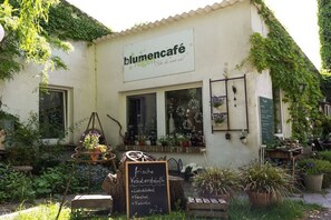 Ein Café mit einem Schild mit dem Aufschrift 'lumencafé' und einer Kreidetafel mit Speisen wie 'frische Kräuterstraupe' und 'Rucola'.