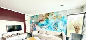 Ein modernes Wohnzimmer mit einem großen abstrakten Gemälde, einem Flachbildfernseher, einer Couch und einem Couchtisch.