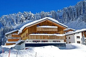 A multi-story wooden chalet with a ski lift, surrounded by snow-covered trees and mountains. - Rothorn - App. Braunarl (Schröcken)