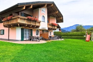 Ein zweistöckiges Gebäude mit Balkonen, Außenplätzen und Blick auf die Berge.