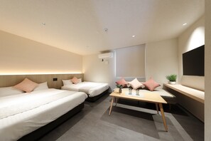 Una habitación de hotel moderna con dos camas, una mesita pequeña y un ventanal grande.