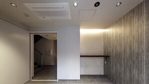 Un pasillo con pared texturizada, una lámpara empotrada en el techo y una puerta que da a otra habitación.