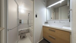 Un baño con ducha, inodoro, lavamanos y espejo.
