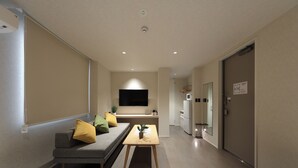 Una habitación de hotel moderna con sofá, una mesita, televisor de pantalla plana y cama.