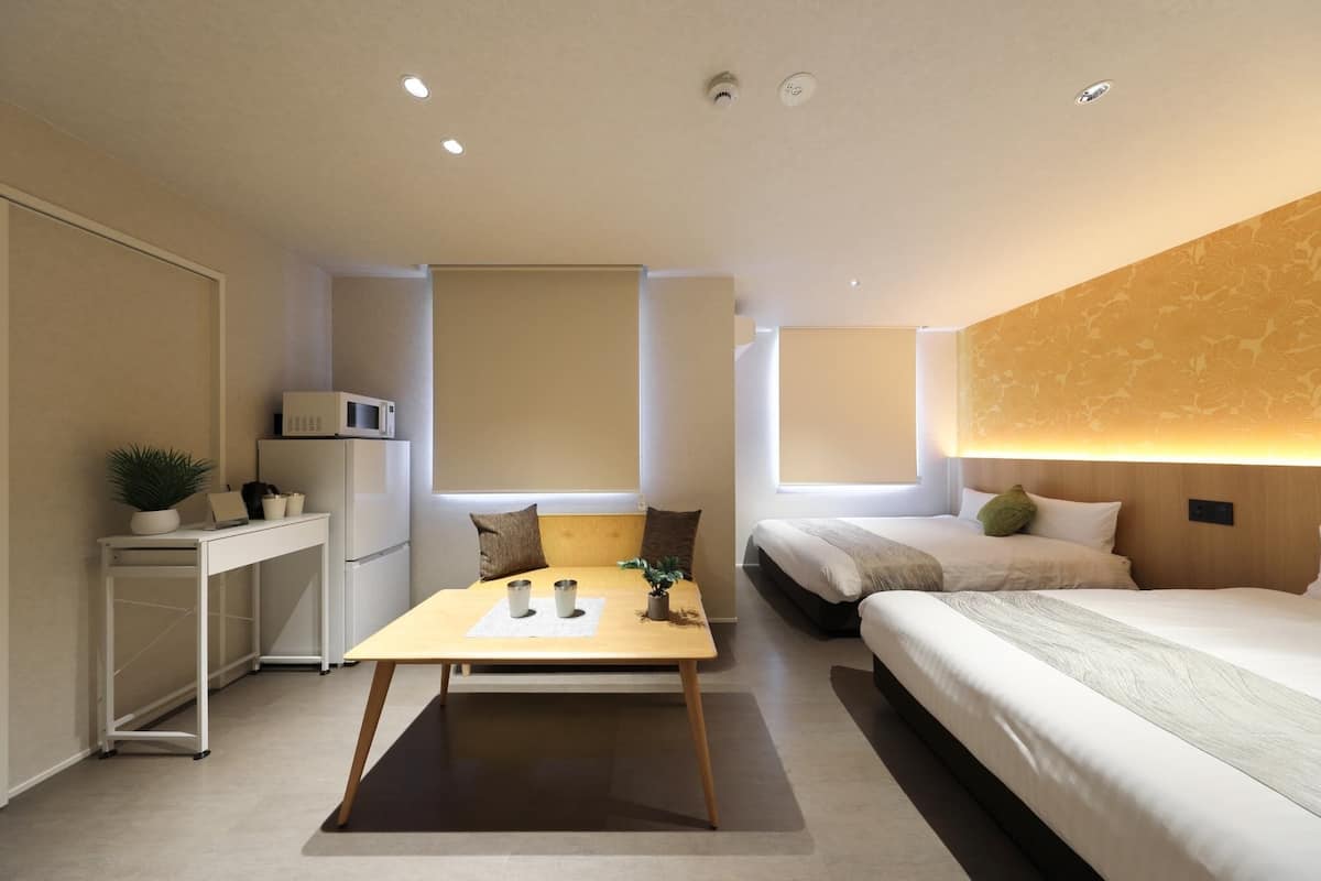 Una habitación de hotel moderna con una cama, un escritorio, un microondas y una pequeña mesa con una planta.