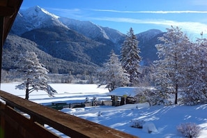 Eine verschneite Berglandschaft mit einer Holzhütte und einem Zaun.
