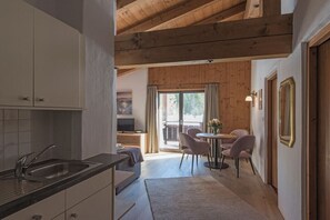 Eine Küche mit Spüle, Schränken und einem Essbereich mit Stühlen und Tisch.