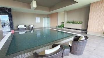 A swimming pool with lounge chairs and a small table.