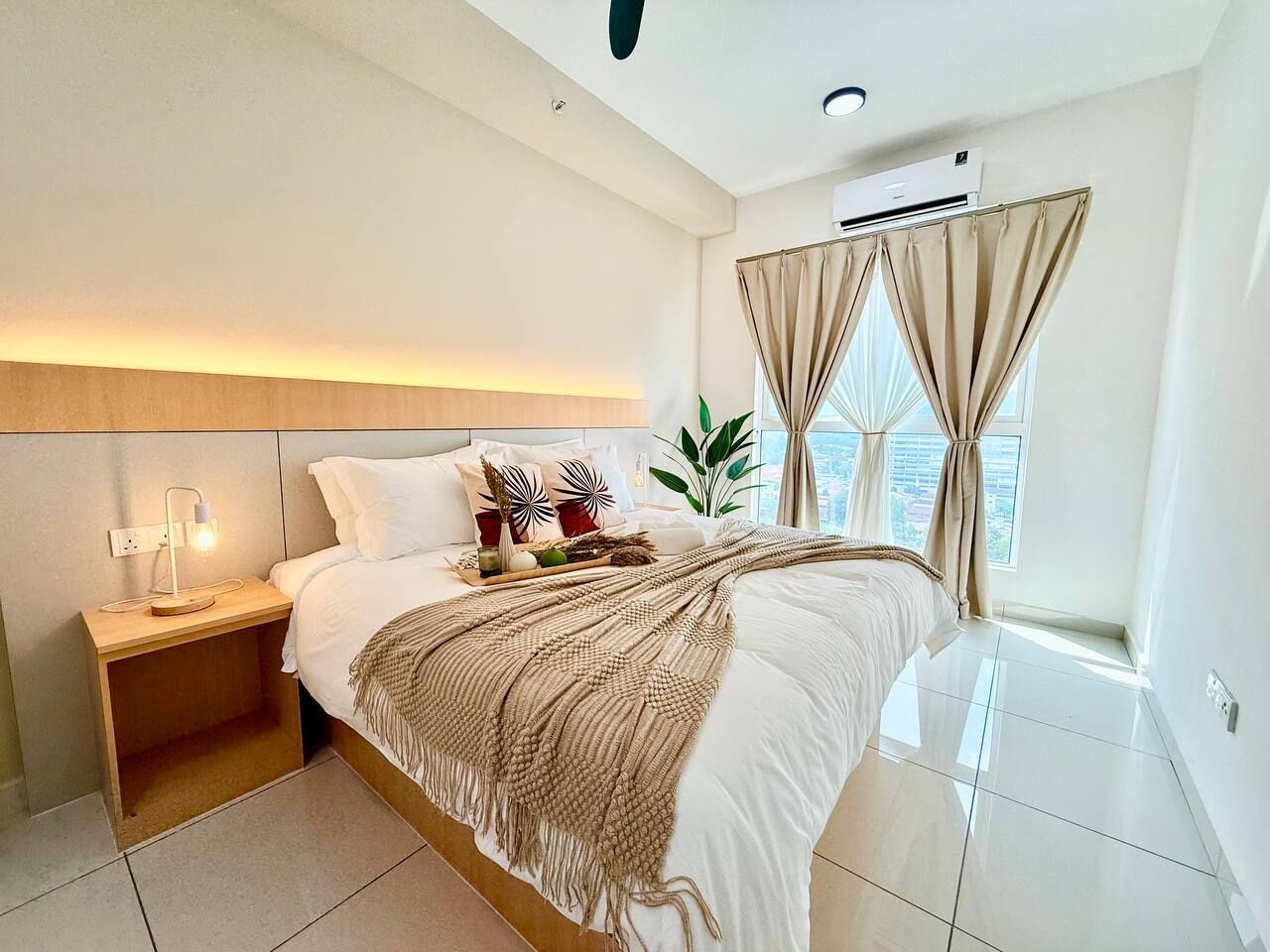 Un dormitorio moderno con cama, mesita de noche, lámpara y cortinas.