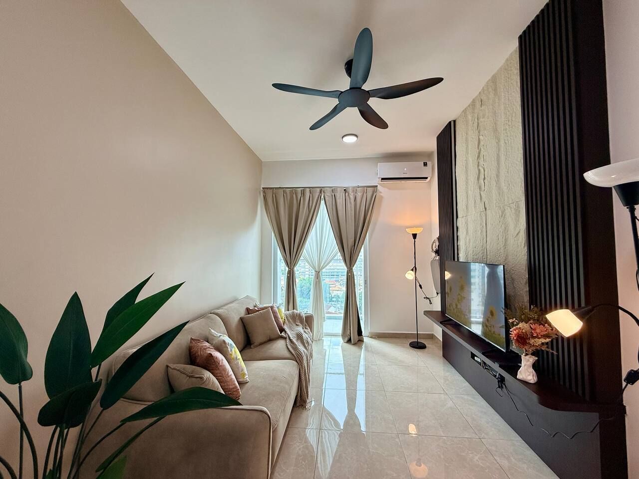 A modern living room with a ceiling fan, a sofa, a TV, and a floor lamp.