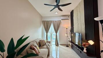 A modern living room with a ceiling fan, a sofa, a TV, and a floor lamp.