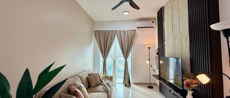 A modern living room with a ceiling fan, a sofa, a TV, and a floor lamp.
