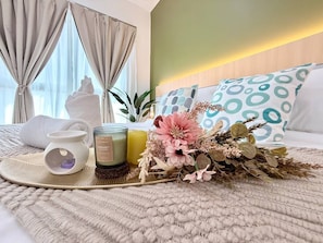A neatly made bed with a white towel, a candle, and a decorative flower arrangement. - OliveSky Suites Ipoh by Grab A Stay  (Ipoh)