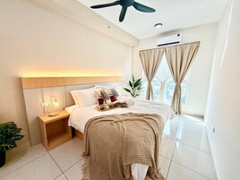 Un dormitorio moderno con cama, mesita de noche, lámpara y cortinas.