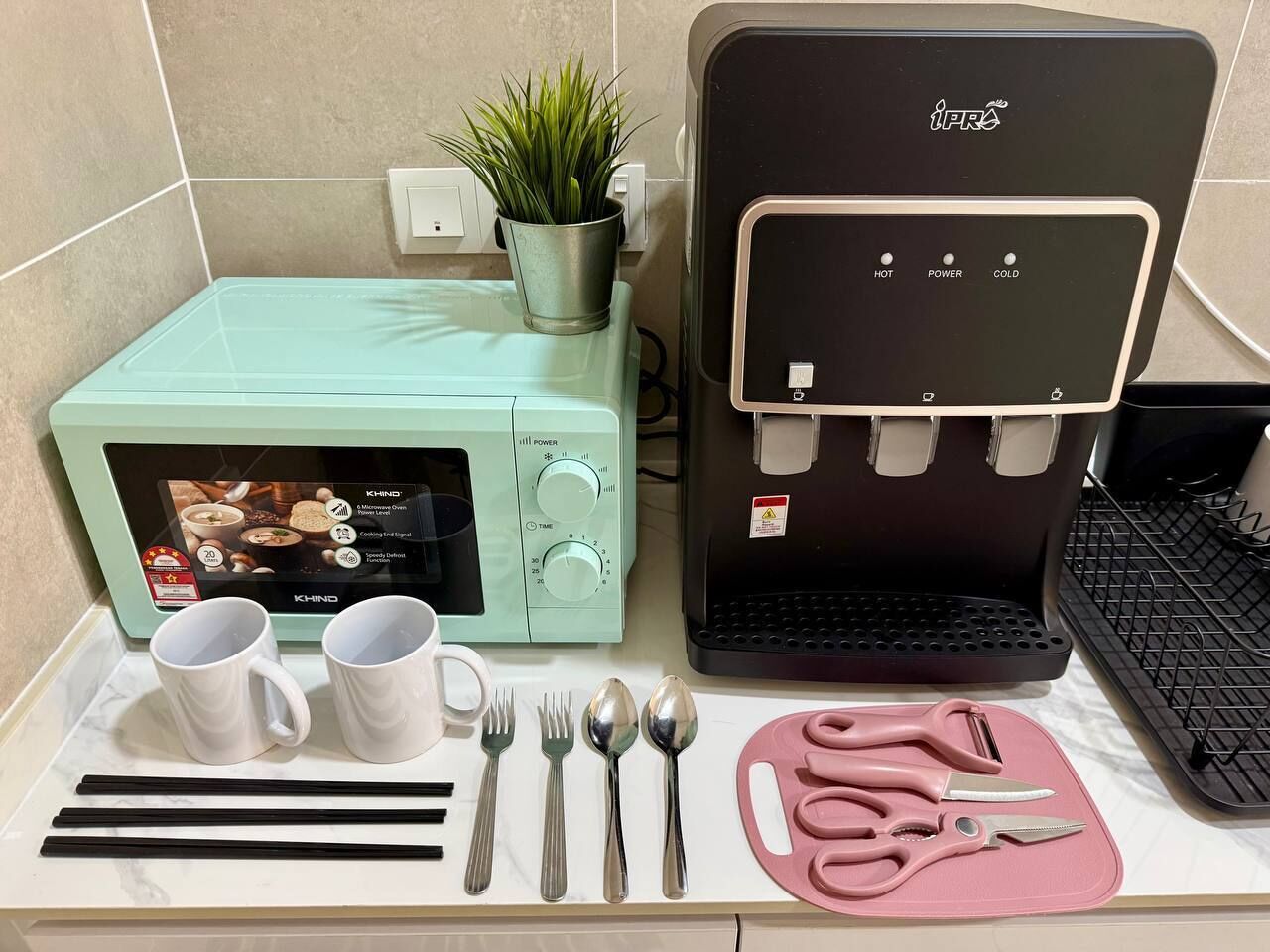 Ett kök med mikrovågsugn, kaffebryggare och köksredskap på bänkskivan.