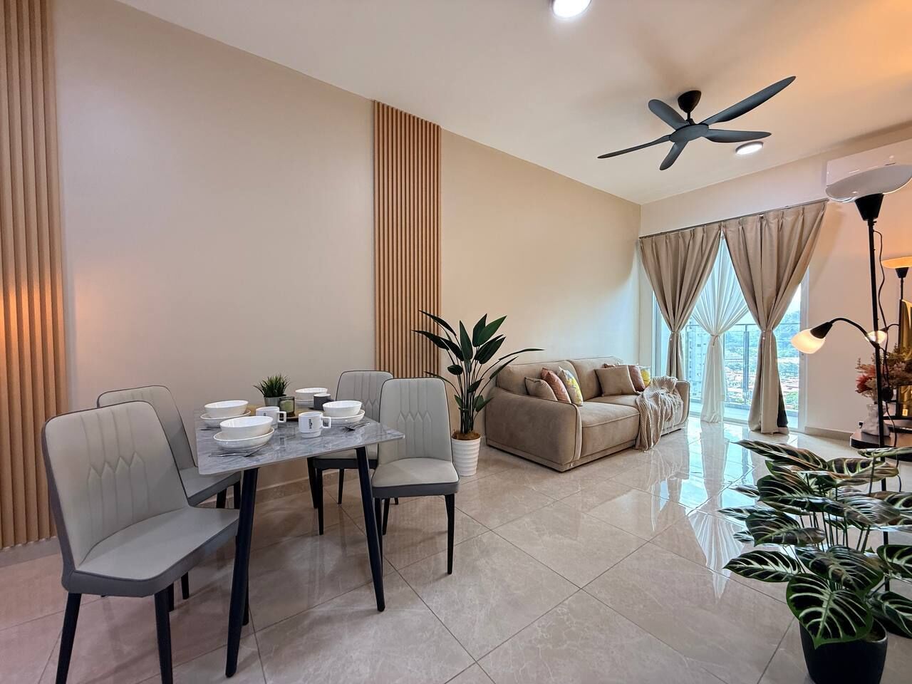 A modern living room with a dining area, a sofa, and a ceiling fan.