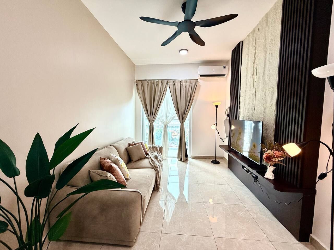 A modern living room with a sofa, a television, and a ceiling fan.