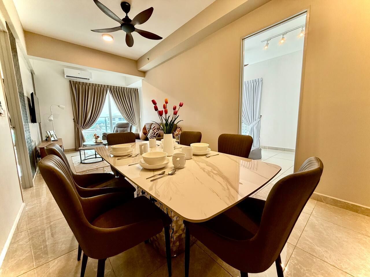 A modern dining area with a marble table, brown upholstered chairs, and a ceiling fan.