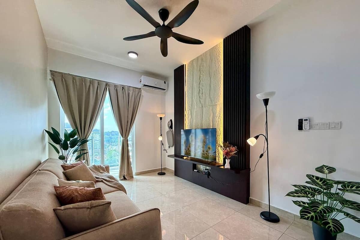 A modern living room with a sofa, TV, floor lamp, and potted plants.
